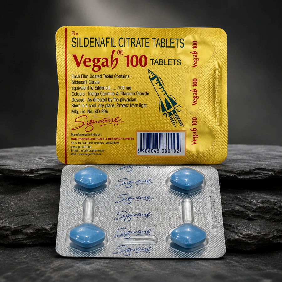 Vega 100 Sildenafil Citrate Tablets packaging shown with a yellow blister pack and a silver foil blister containing four blue tablets, set against a dark textured stone background.